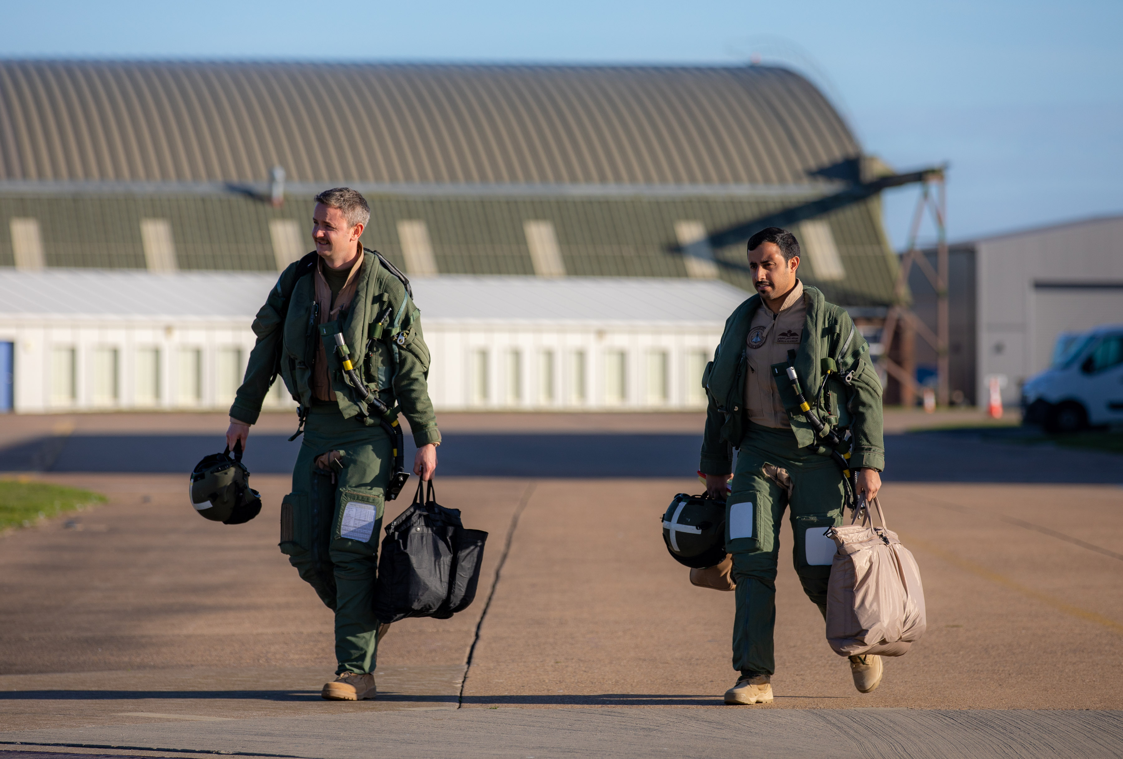 Image shows RAF Pilots walking across airfield with bags.